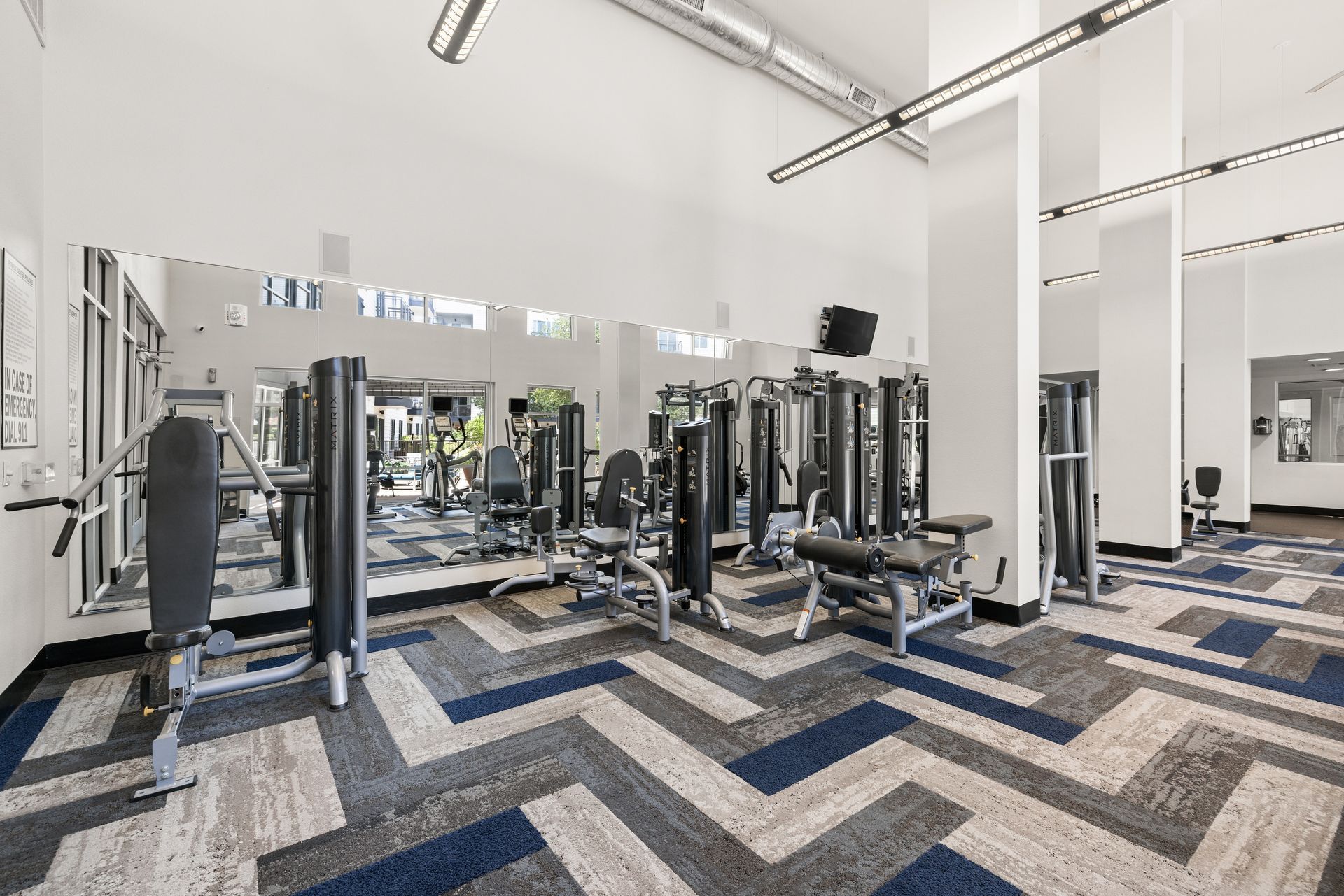 Modern gym interior with weight machines, mirrors, and patterned carpet