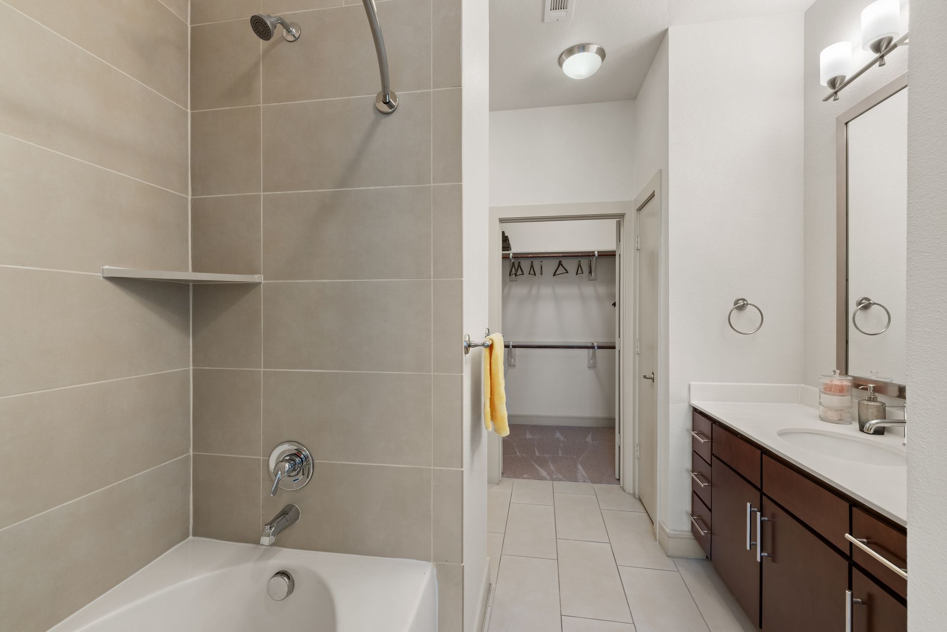 Bright bathroom with bathtub, shower, vanity, and open doorway to a closet at Sabina in Austin, TX.