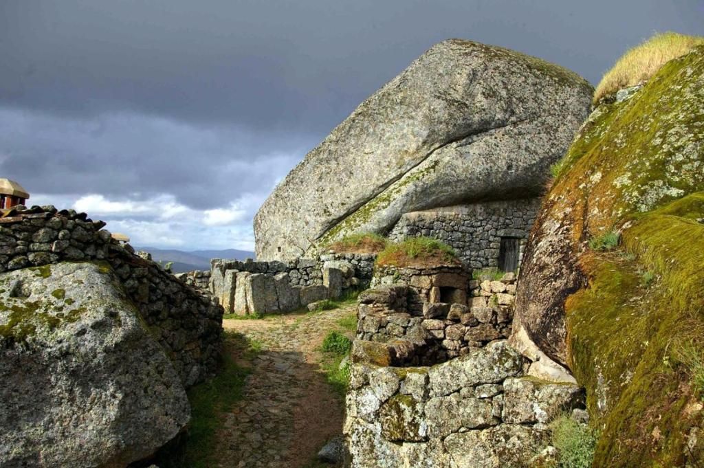 Paisagem costeira rochosa com grandes blocos de pedra, pedras cobertas de musgo e céu nublado