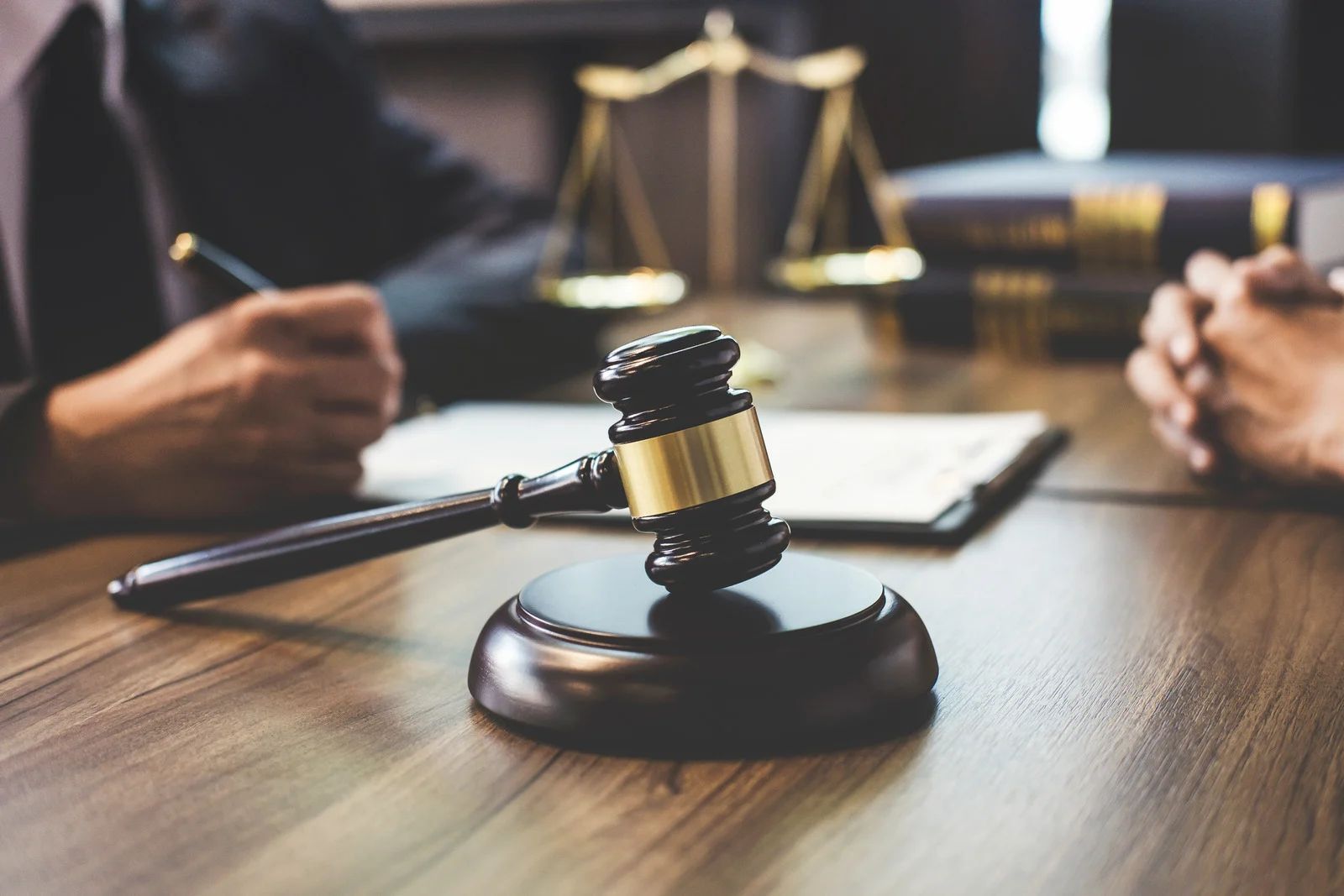 Lawyer’s desk with gavel, scales of justice, and people discussing a case