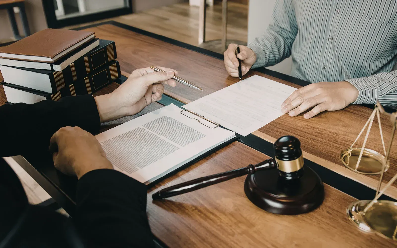 People reviewing legal documents at a desk with a gavel and books