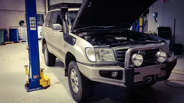 a toyota land cruiser with its hood open is on a lift in a garage .