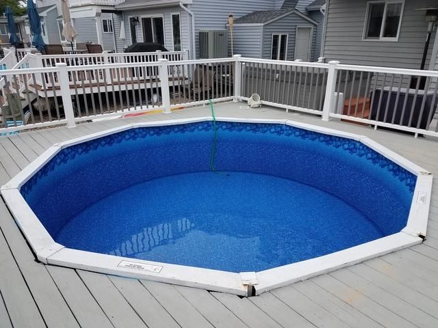 A swimming pool on a deck with a white railing