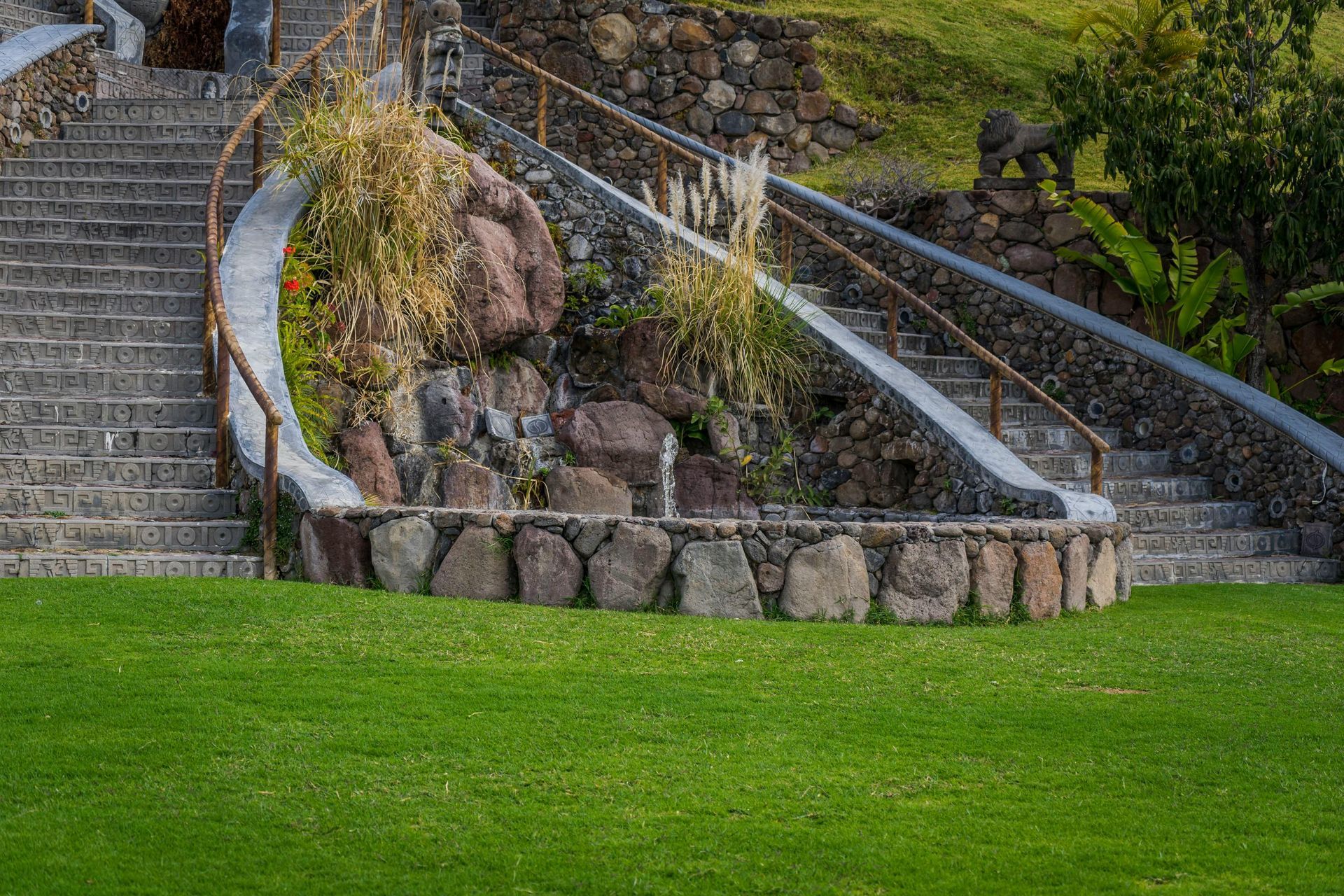 Stone stairways flank a landscaped rock garden above a bright green lawn