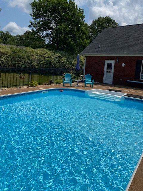 A large swimming pool in front of a red house
