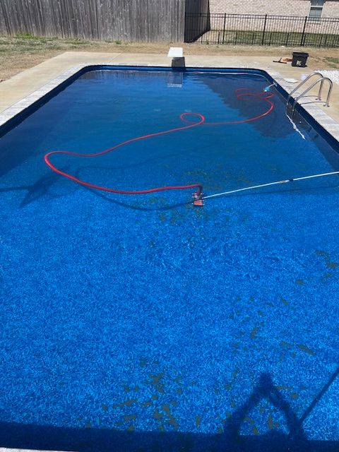 A large blue swimming pool with a red hose in it.
