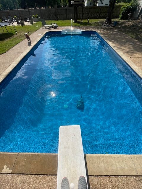 A person standing on a diving board in front of a large swimming pool