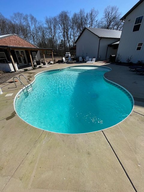 A large swimming pool with a house in the background