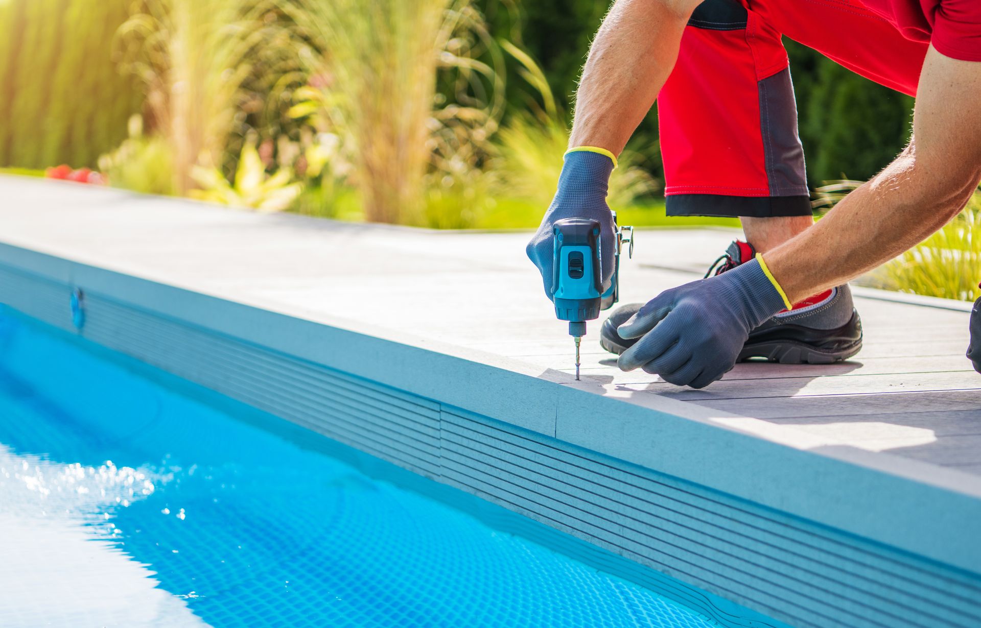 A man is working on a swimming pool with a drill.