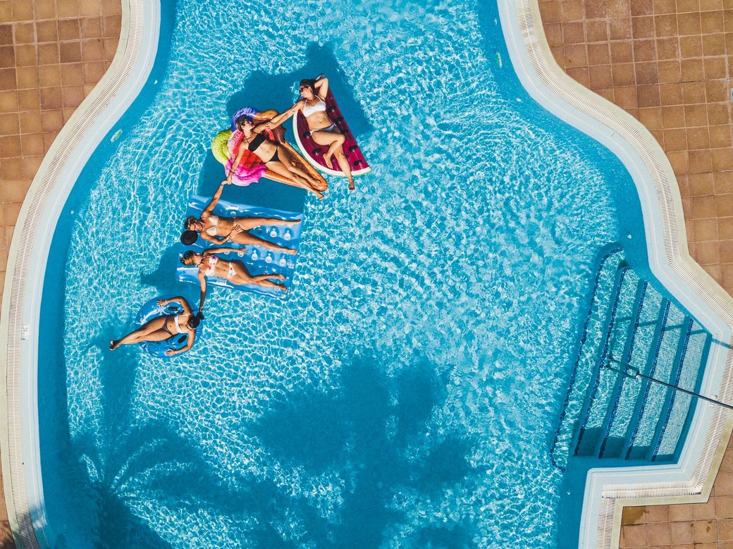 A group of people are floating on rafts in a swimming pool.