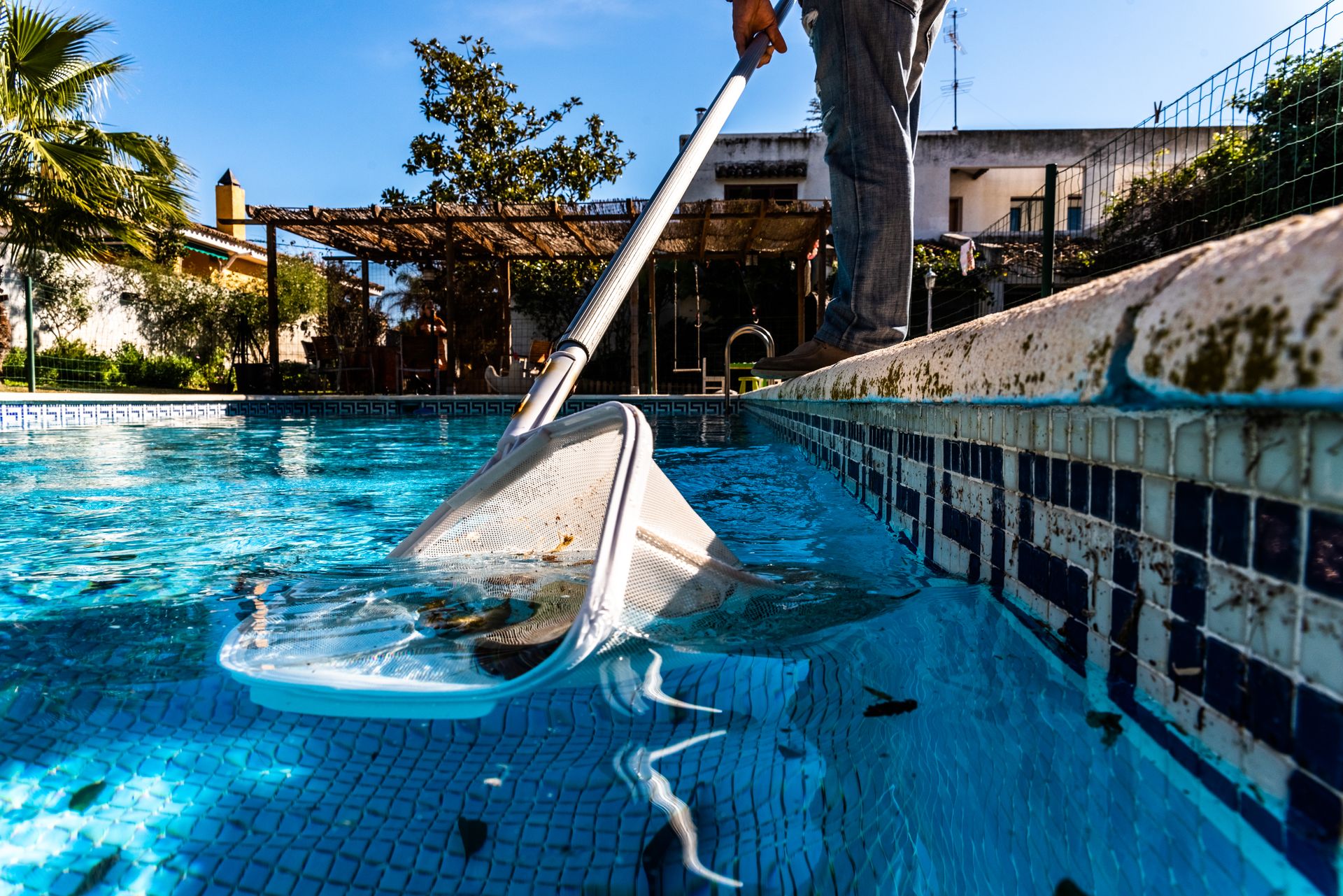 A person is cleaning a swimming pool with a vacuum cleaner.