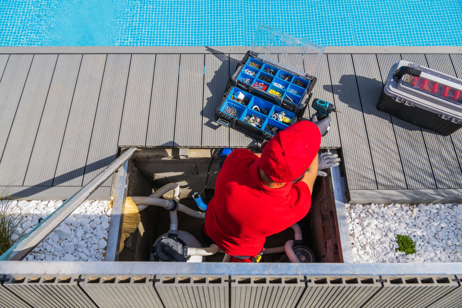 A man in a red shirt is working on a swimming pool.