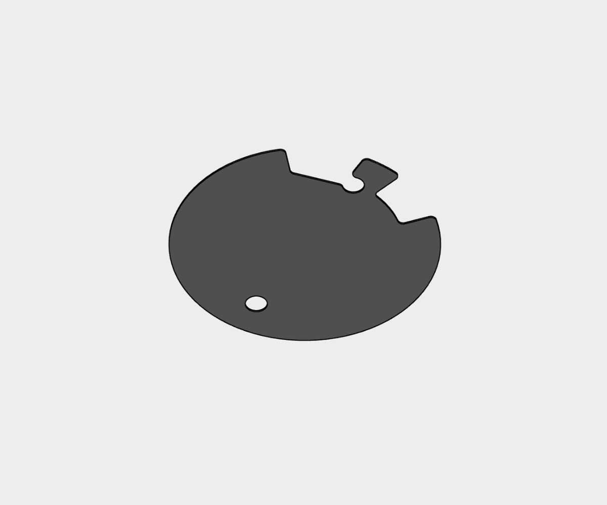 A circular, dark gray component with two cutouts and a small protruding tab along the edge, plus a tiny central hole.