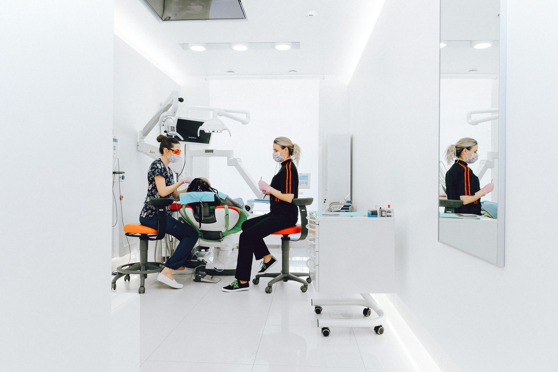 Two women are sitting in a dental office talking to each other.