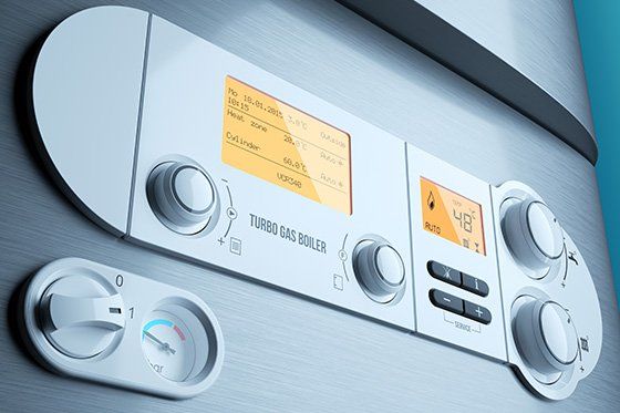 Primo piano del pannello di controllo di una moderna caldaia a gas con display digitale e quadranti.