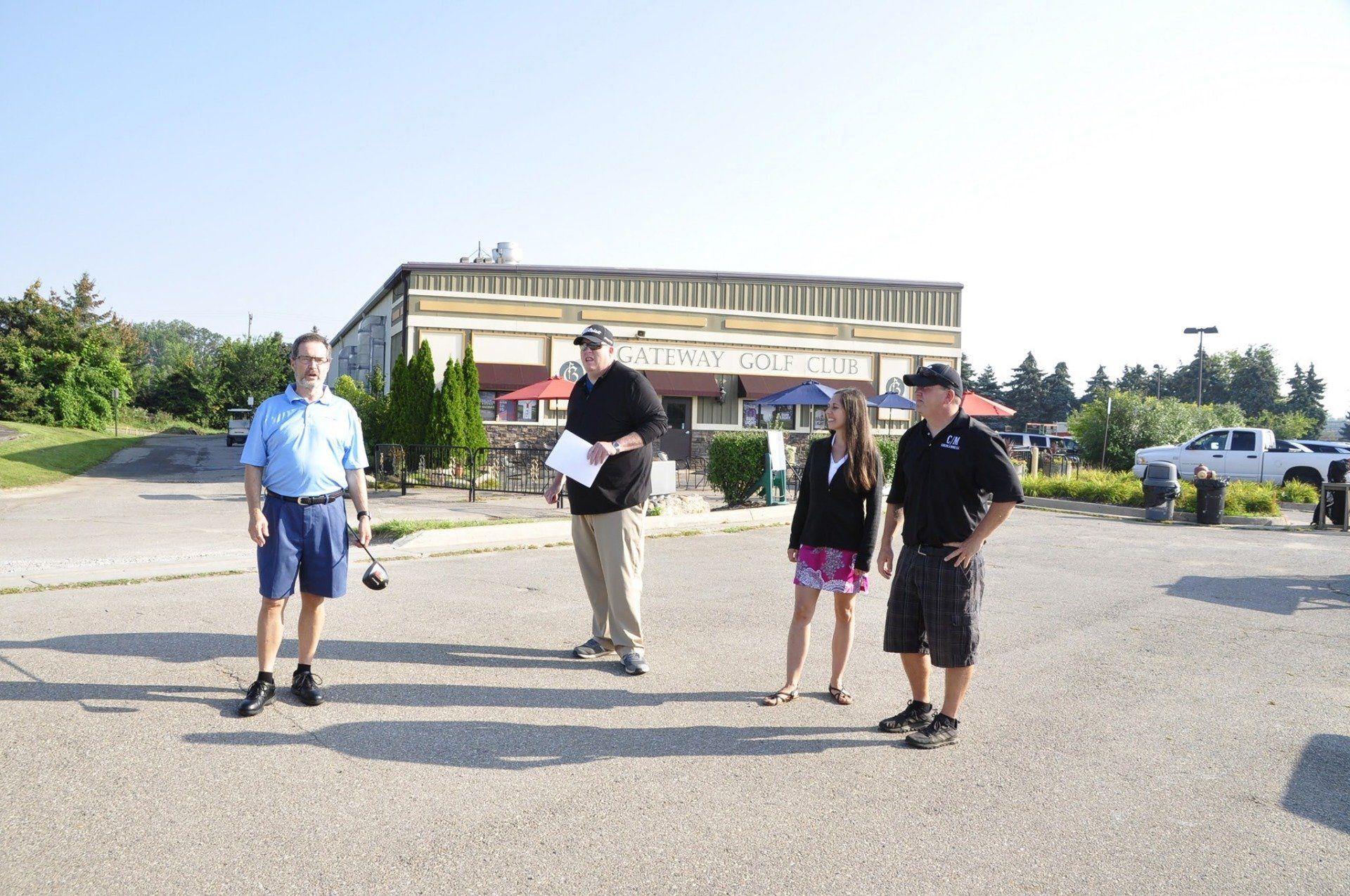 Four people stand in a parking lot in front of a building with a sign that says 