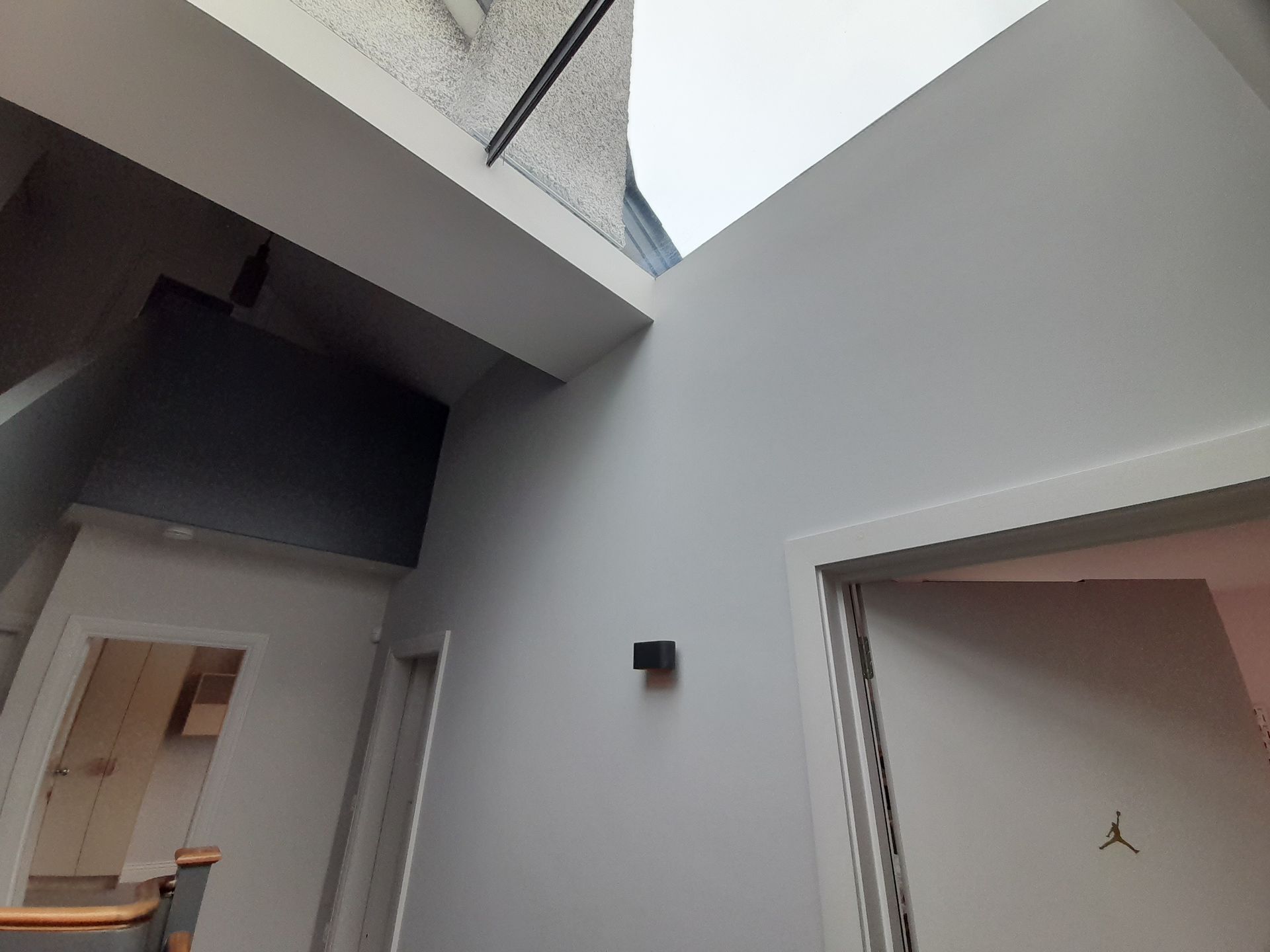Indoor hallway with white walls, open doorways, and a skylight overhead