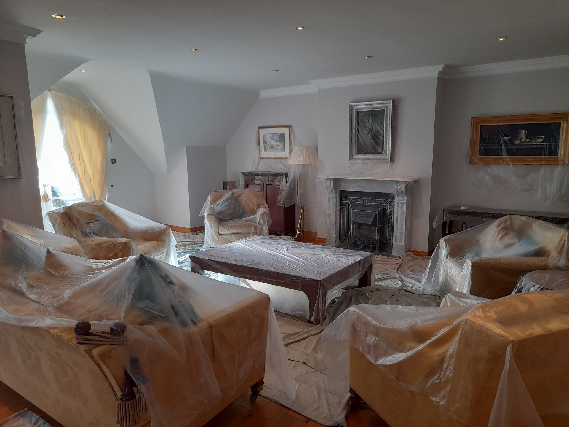 Living room with sofas covered in plastic, a coffee table, and a fireplace