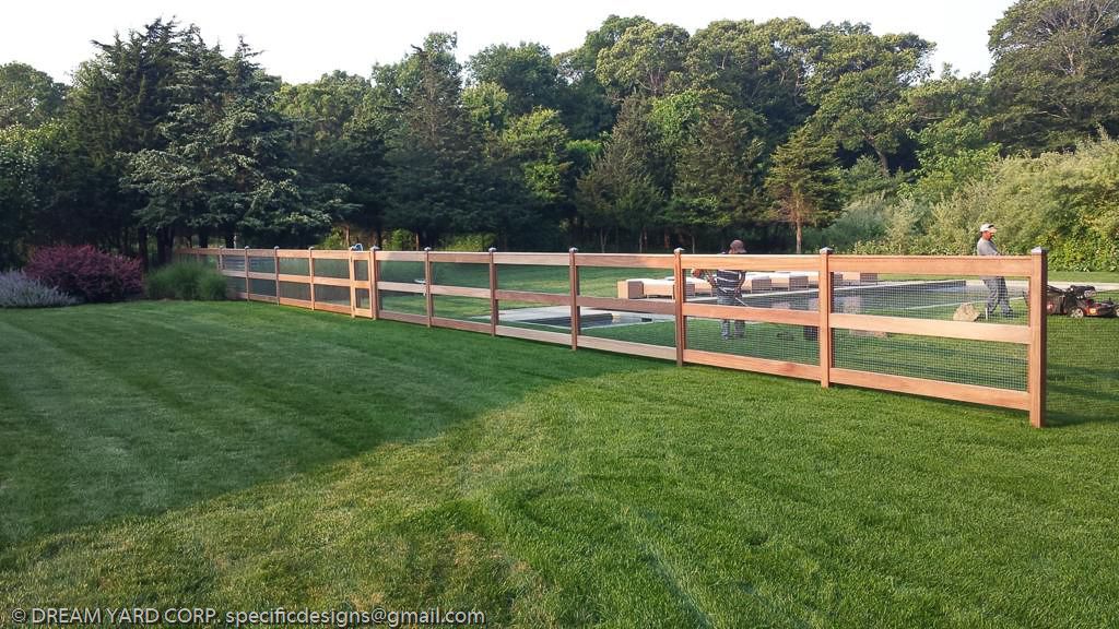 Dreamyard Landscaping, Inc. | Fencing - Southampton, NY Wooden fence encloses a grassy backyard, with trees in the background.