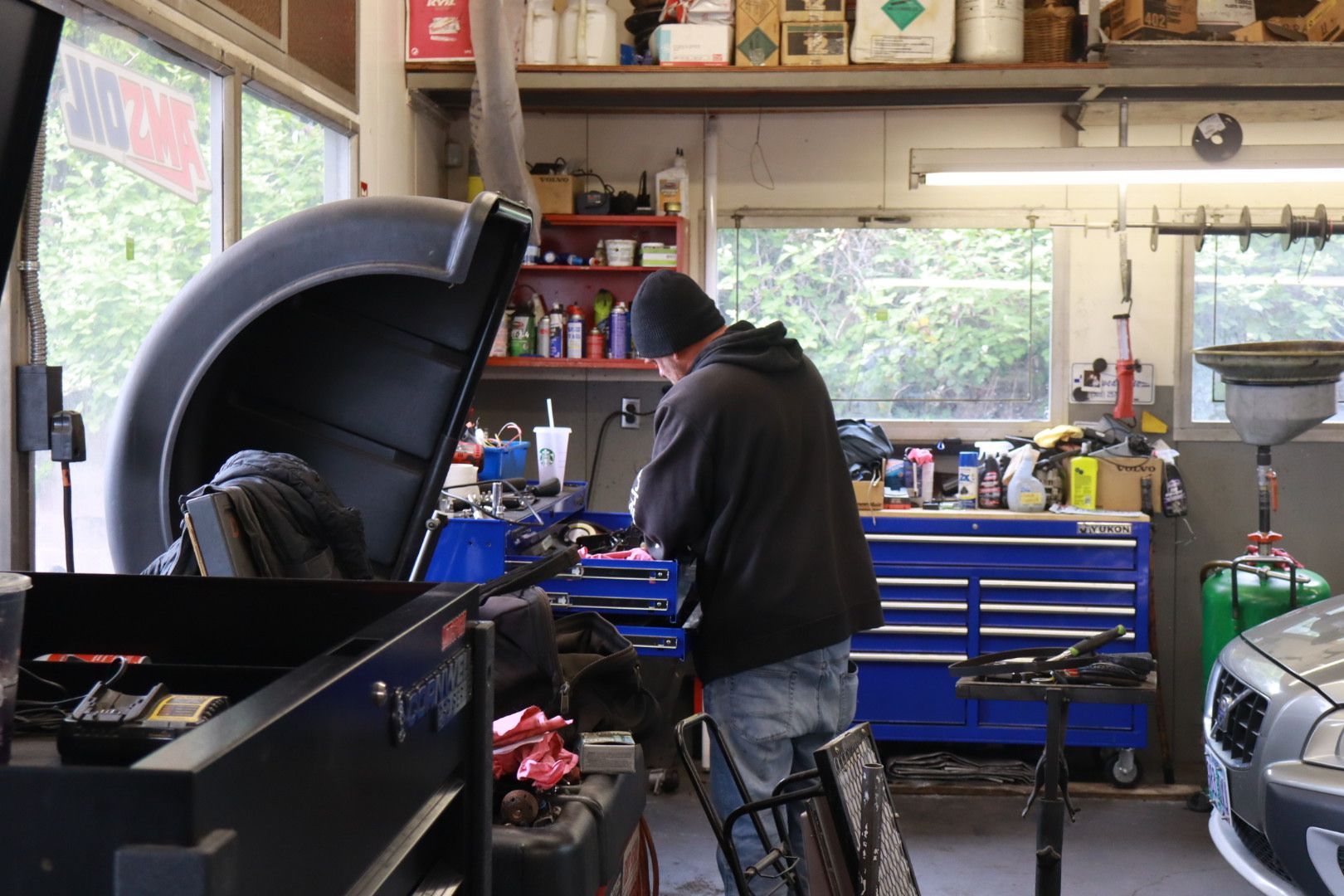 Person working at a bicycle repair station in a garage with tool chests and car parts