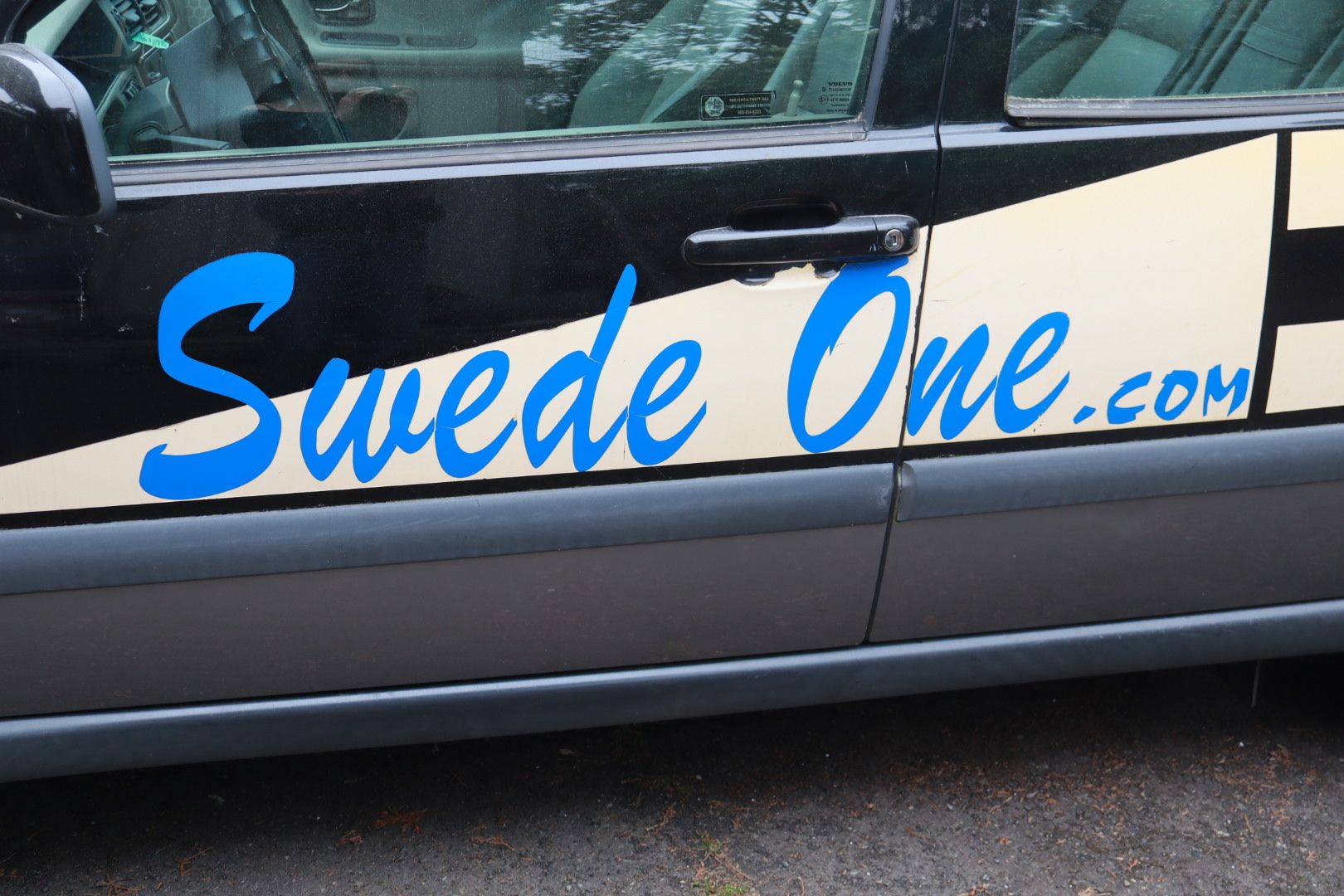 Black car door with blue and white “Swede One.com” lettering on the side