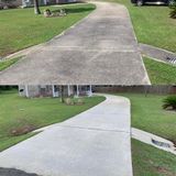 Before-and-after comparison of a concrete driveway, showing a dirty, dark surface cleaned to a bright, uniform gray.