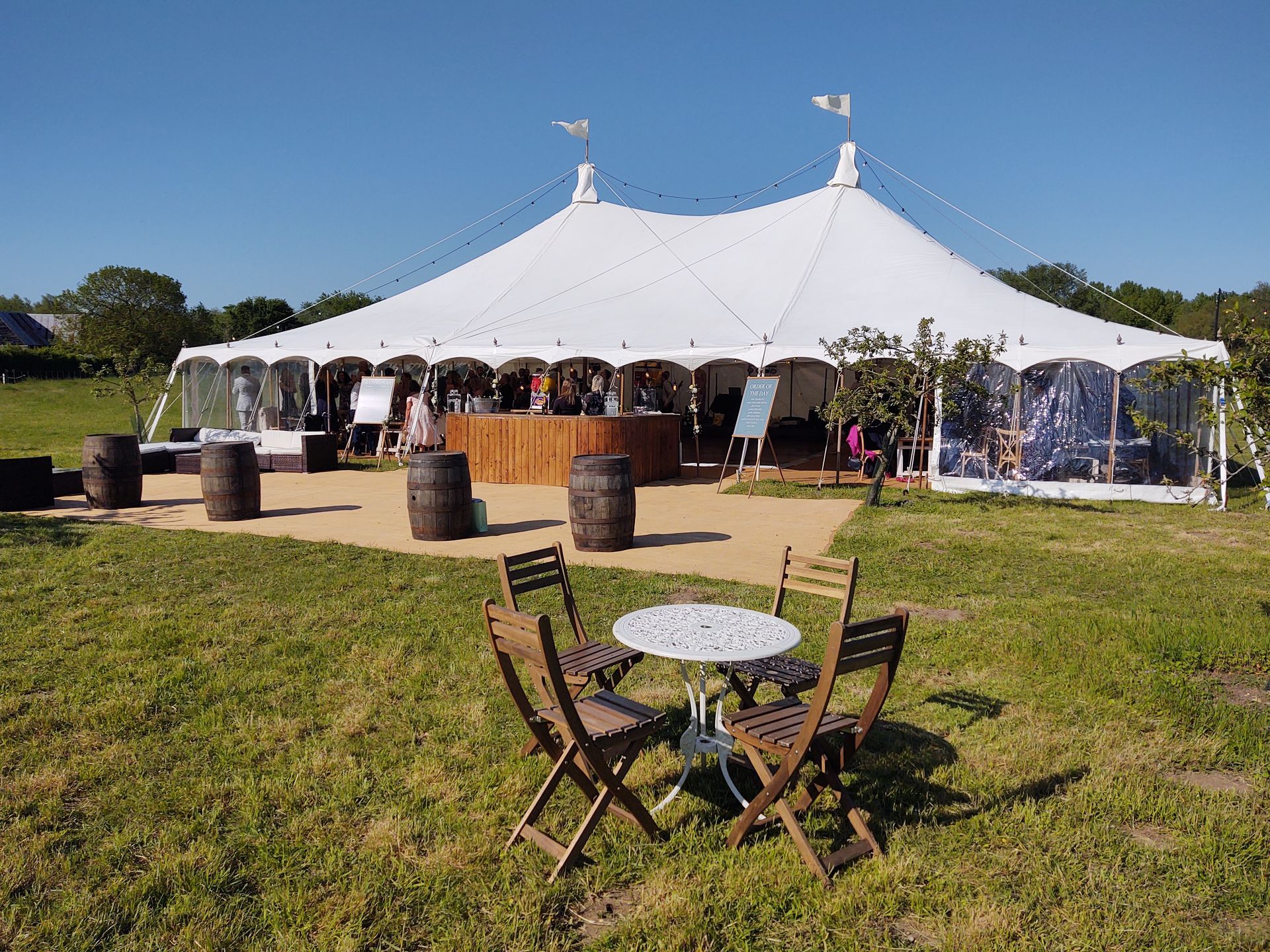 White event tent on a grassy lawn with outdoor seating and a small table in front