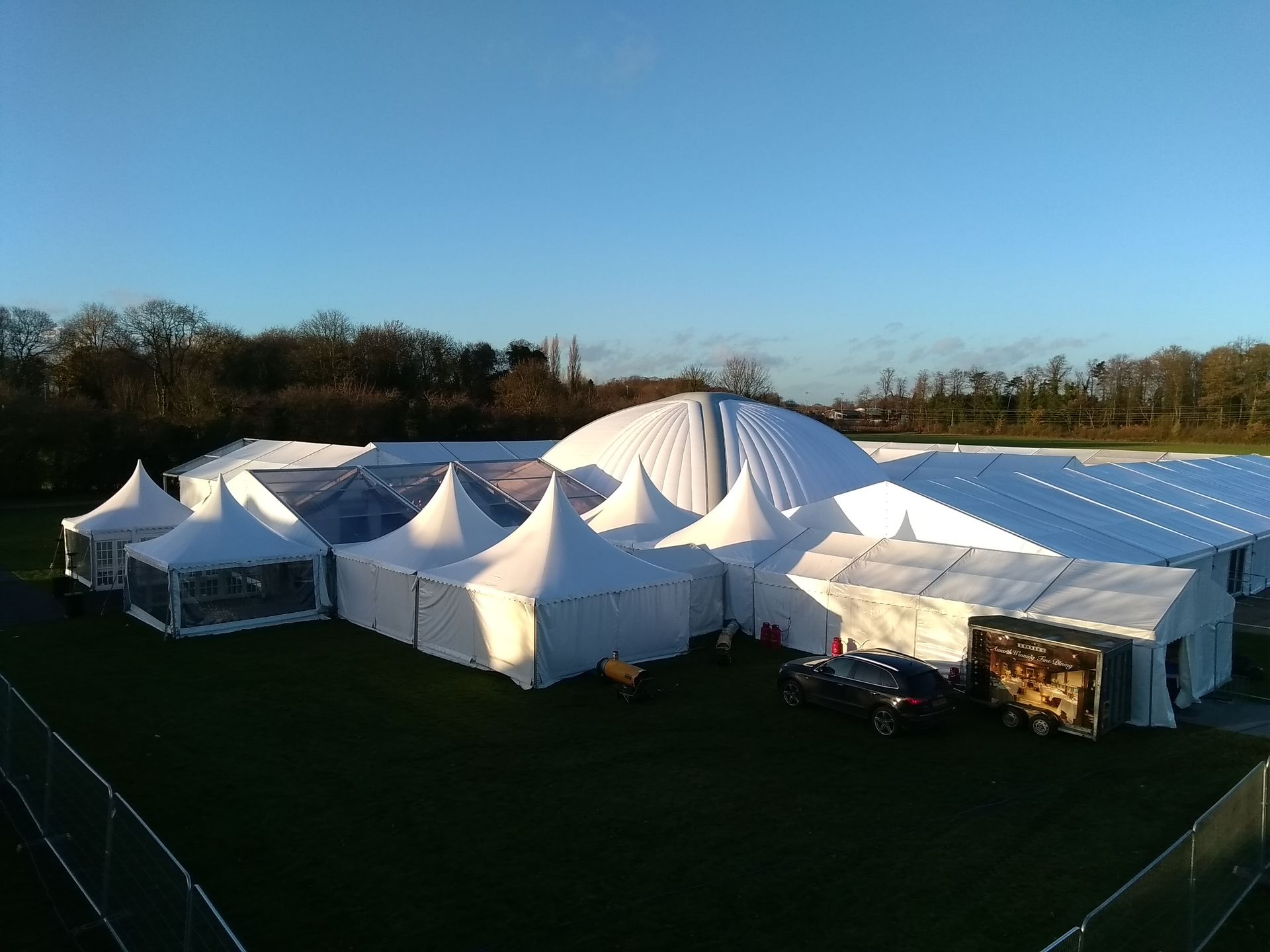 Large white event tents on a grassy field under a clear blue sky