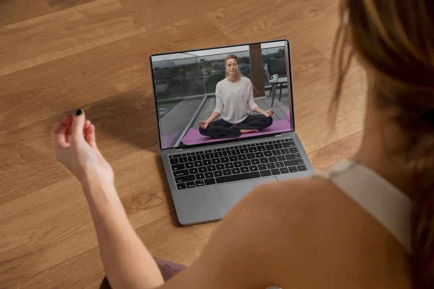 una mujer mira una clase de yoga en una computadora portátil