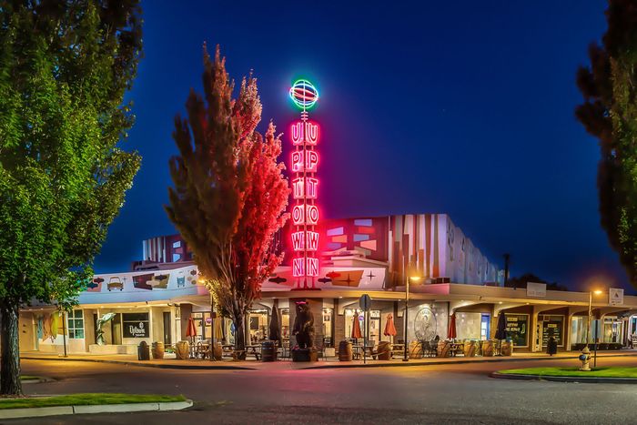 The Tower Theatre in Bend, Oregon, at night, featuring a tall, illuminated neon sign against a deep blue sky.