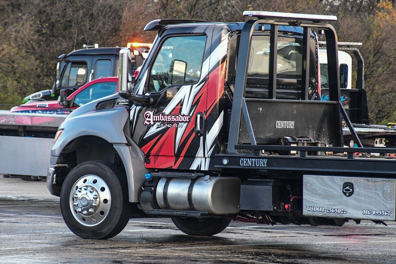 Tow truck with red and white graphics, parked outside.