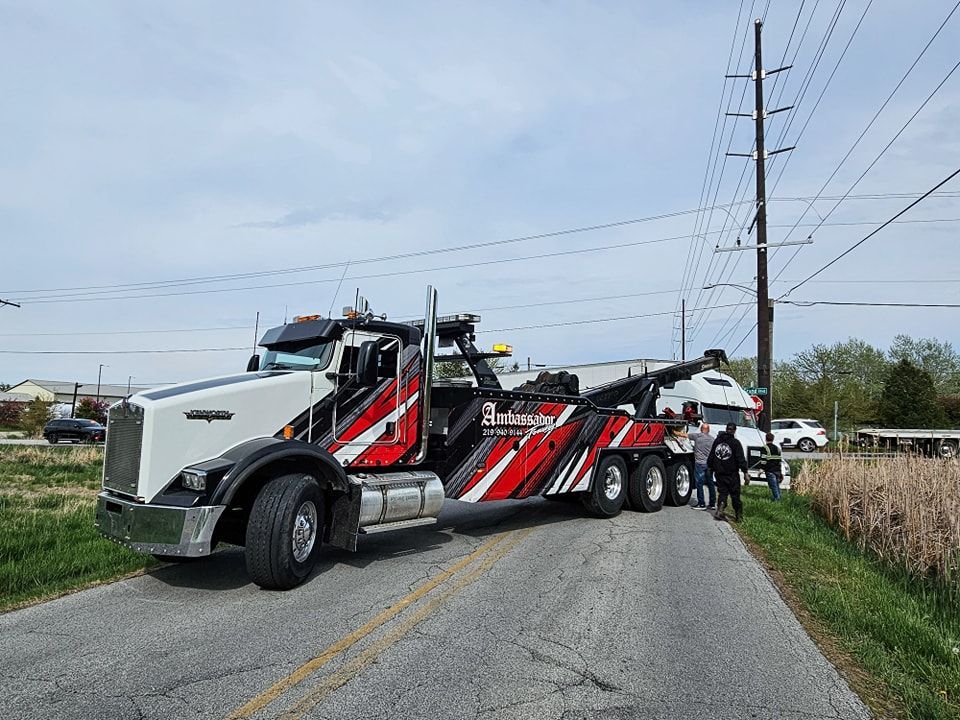 Tow truck with white car on the hook, roadside near power lines.