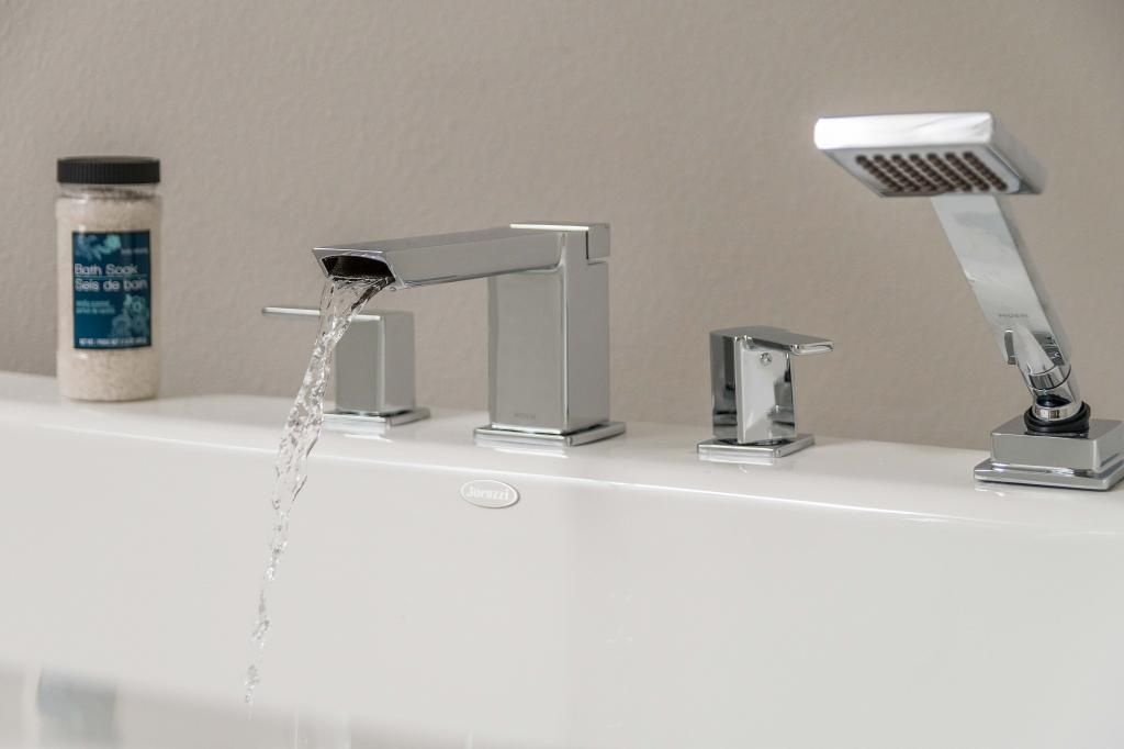 Modern bathroom sink with running water, faucet, soap dispenser, and handheld showerhead