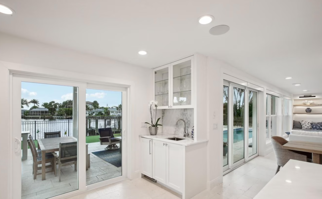 Bright modern kitchen with white cabinets, sliding glass doors, and a water view outside