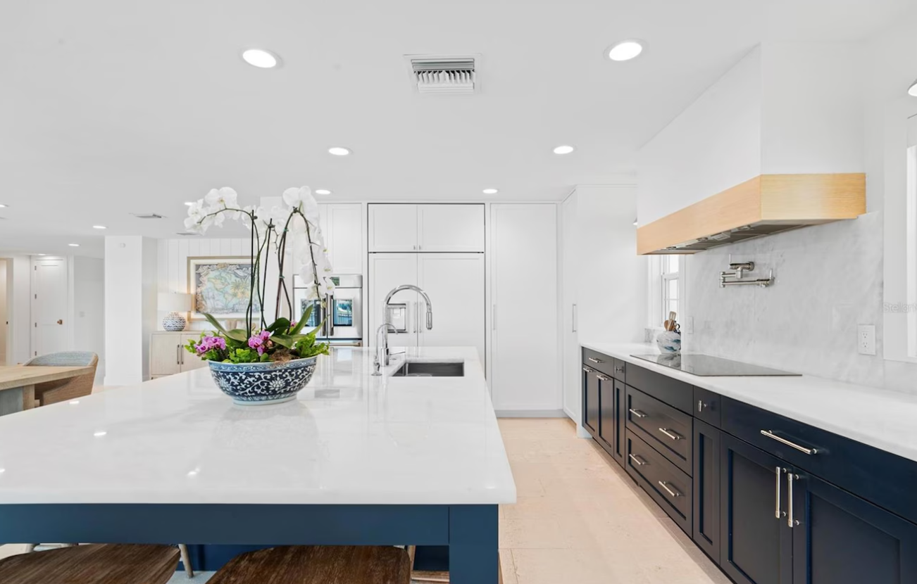 Bright modern kitchen with white island, dark cabinets, and a fruit centerpiece