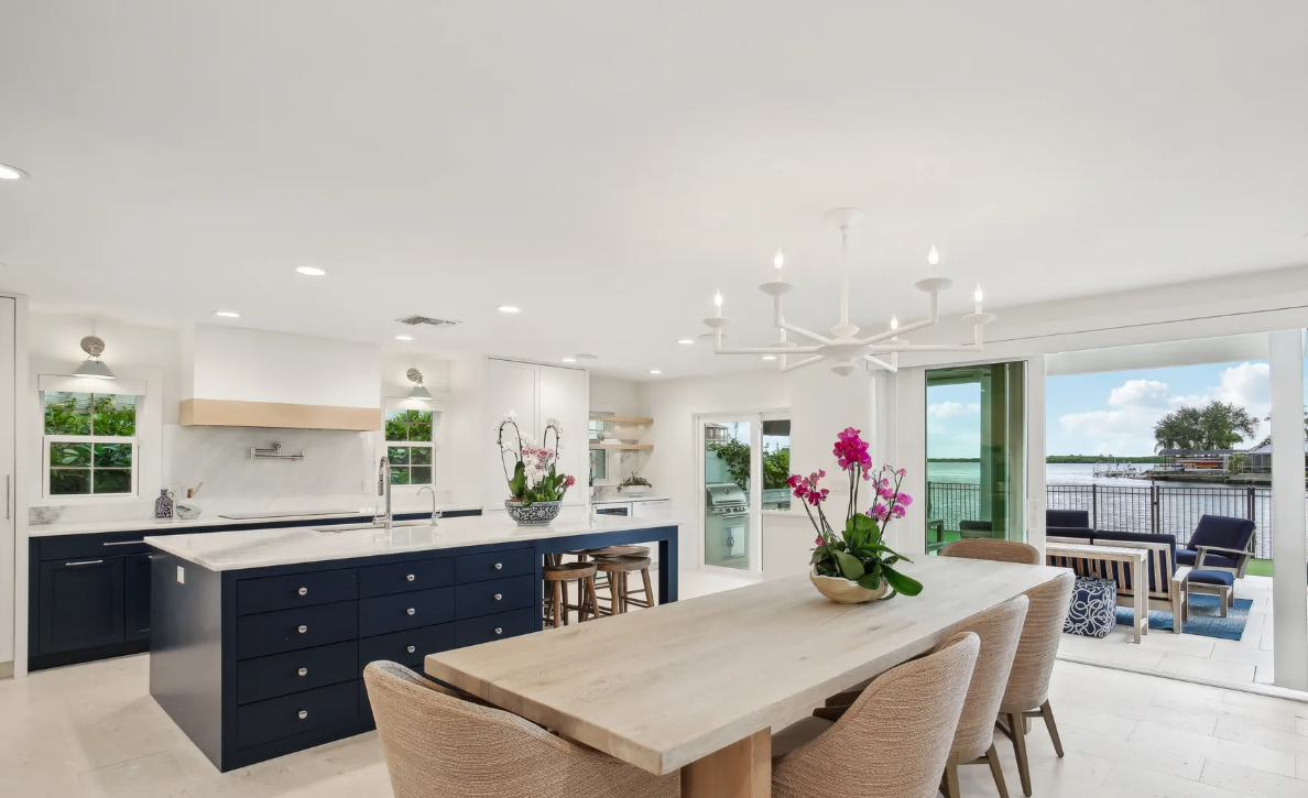Bright open-plan kitchen and dining area with a wooden table, navy island, and sliding doors to a patio.