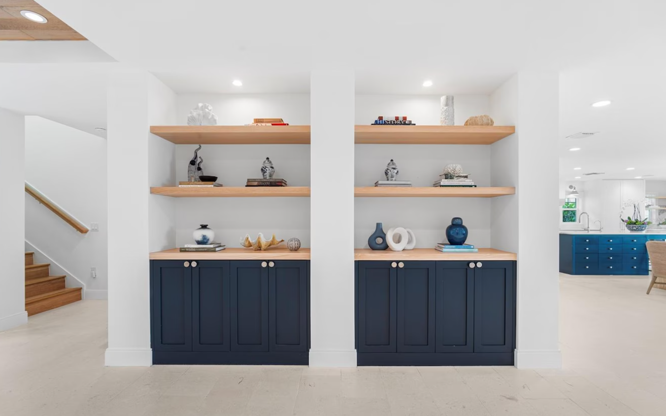 Bright modern living room wall with built-in shelves, navy cabinets, and decor accents