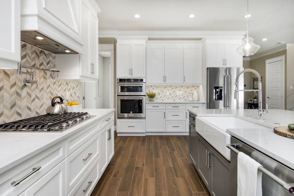 Bright white modern kitchen with island, stainless appliances, and wood floors