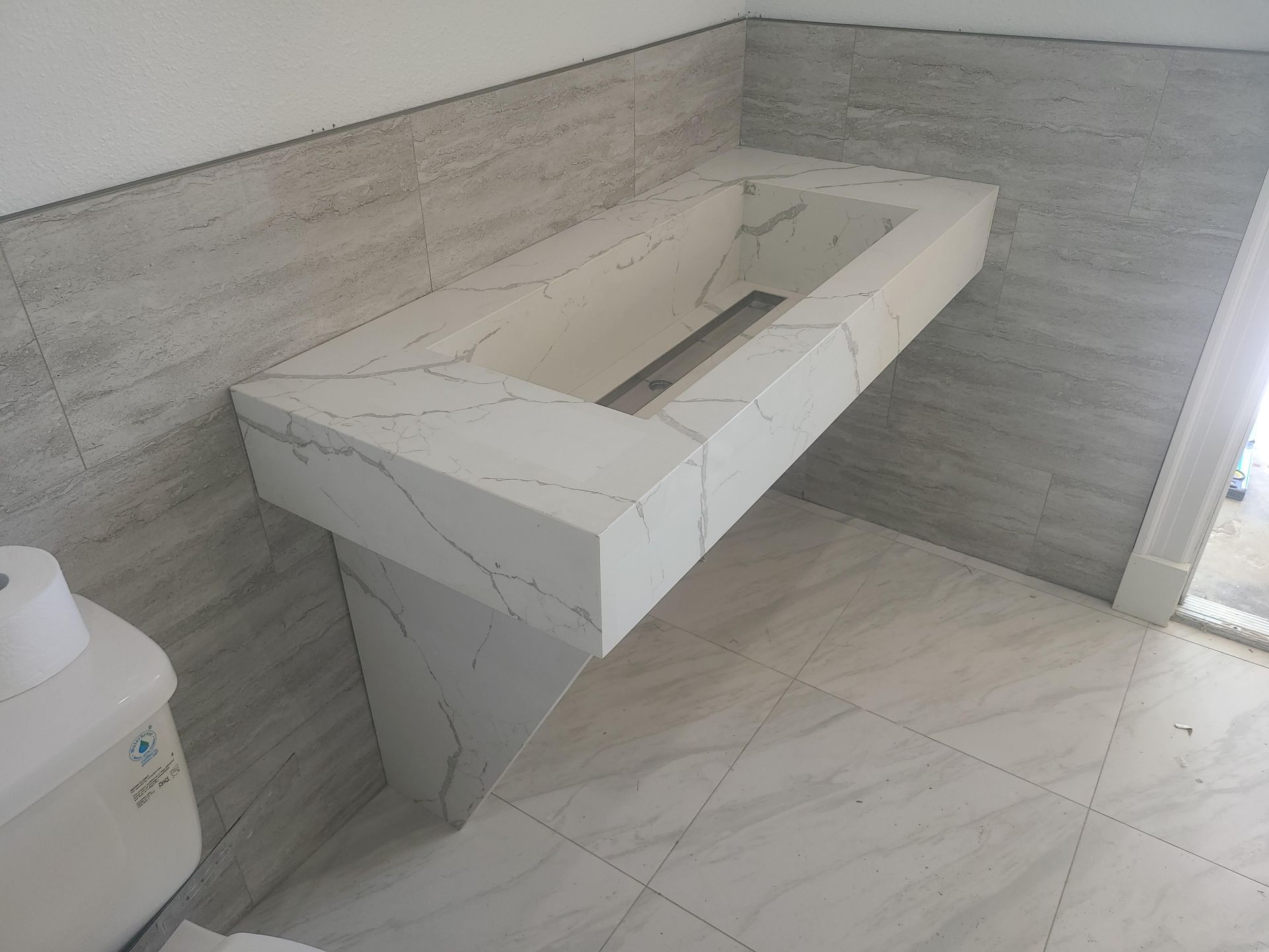 Modern bathroom with white marble vanity and rectangular sink against gray tiled walls and floor