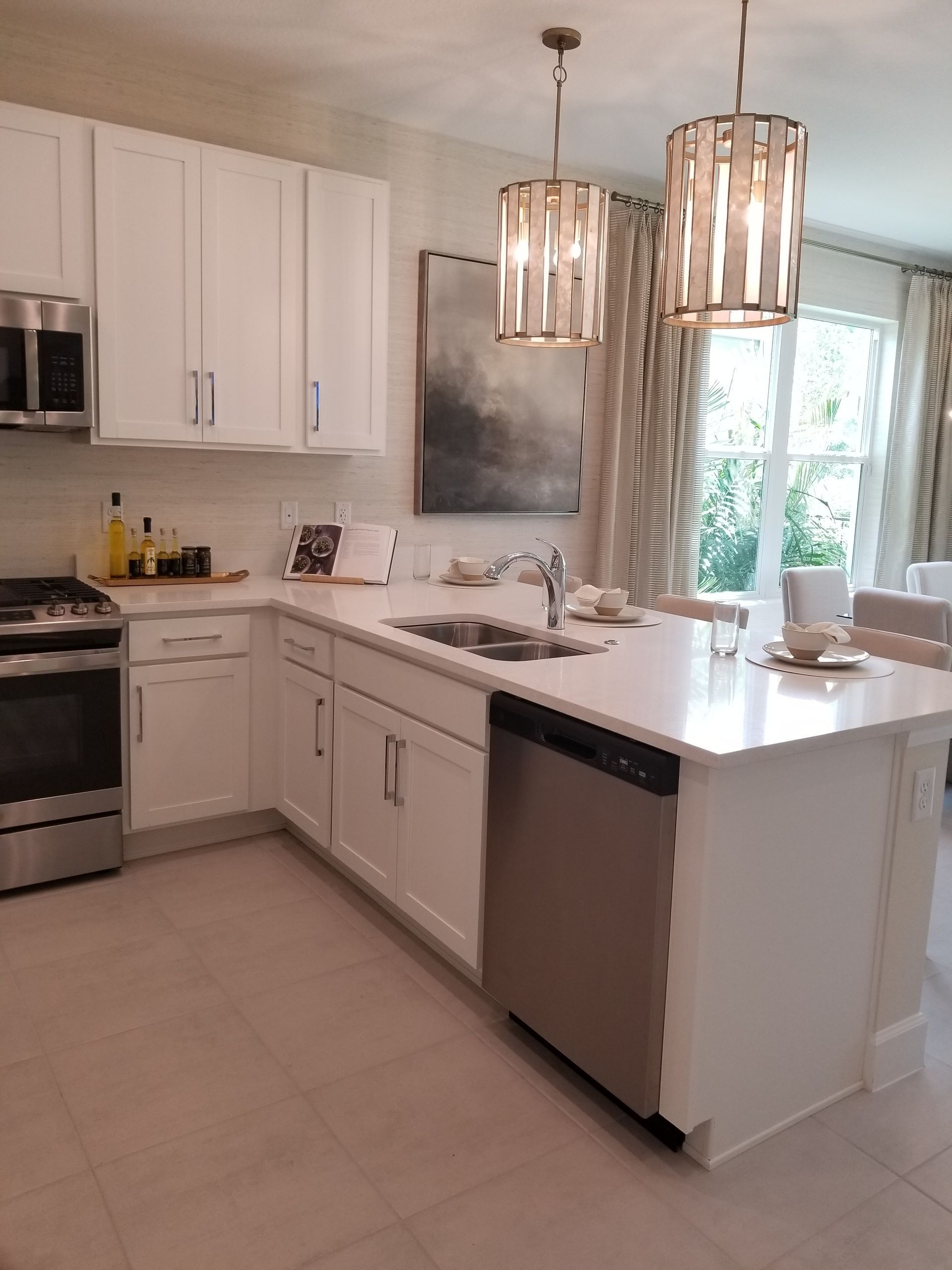 Bright modern kitchen with white cabinets, island, pendant lights, and stainless steel appliances