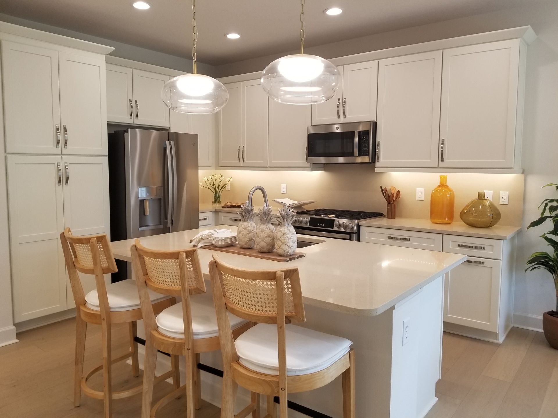 Bright modern kitchen with white cabinets, stainless appliances, and a light wood island with bar stools