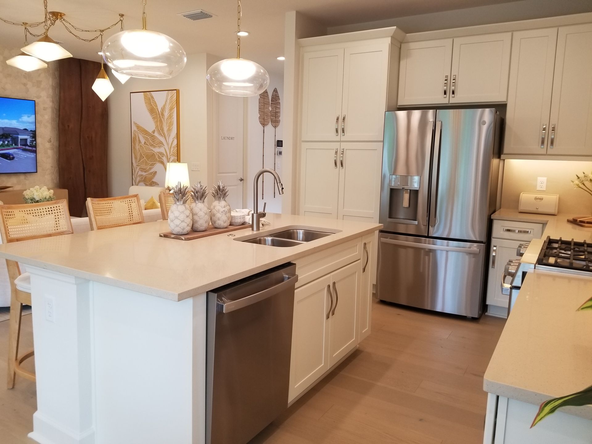 Modern kitchen with white cabinets, stainless steel appliances, marble island, and pendant lights