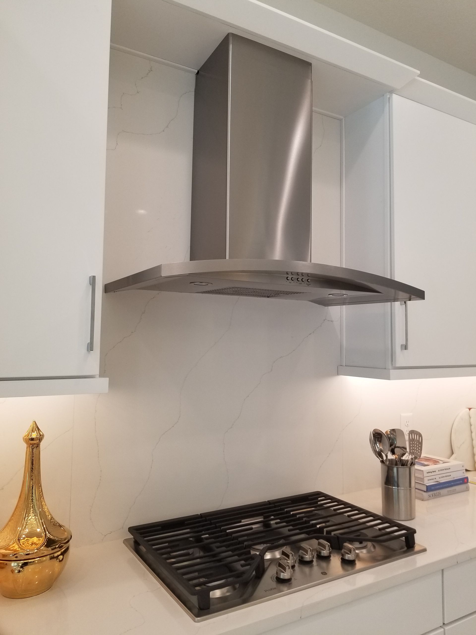 Modern kitchen stove with stainless steel range hood and white cabinets