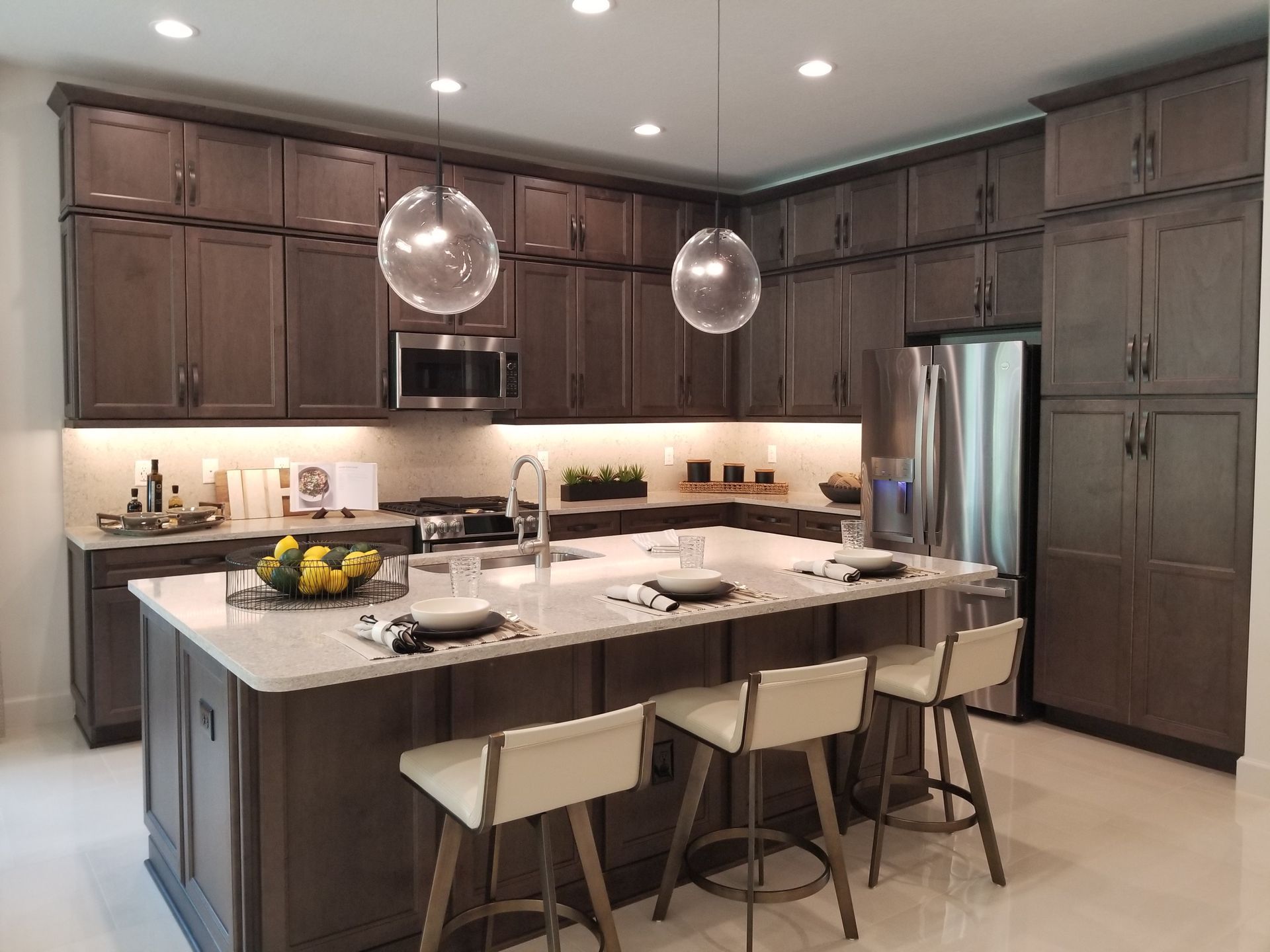 Modern kitchen with dark cabinets, large island, pendant lights, and stainless-steel appliances