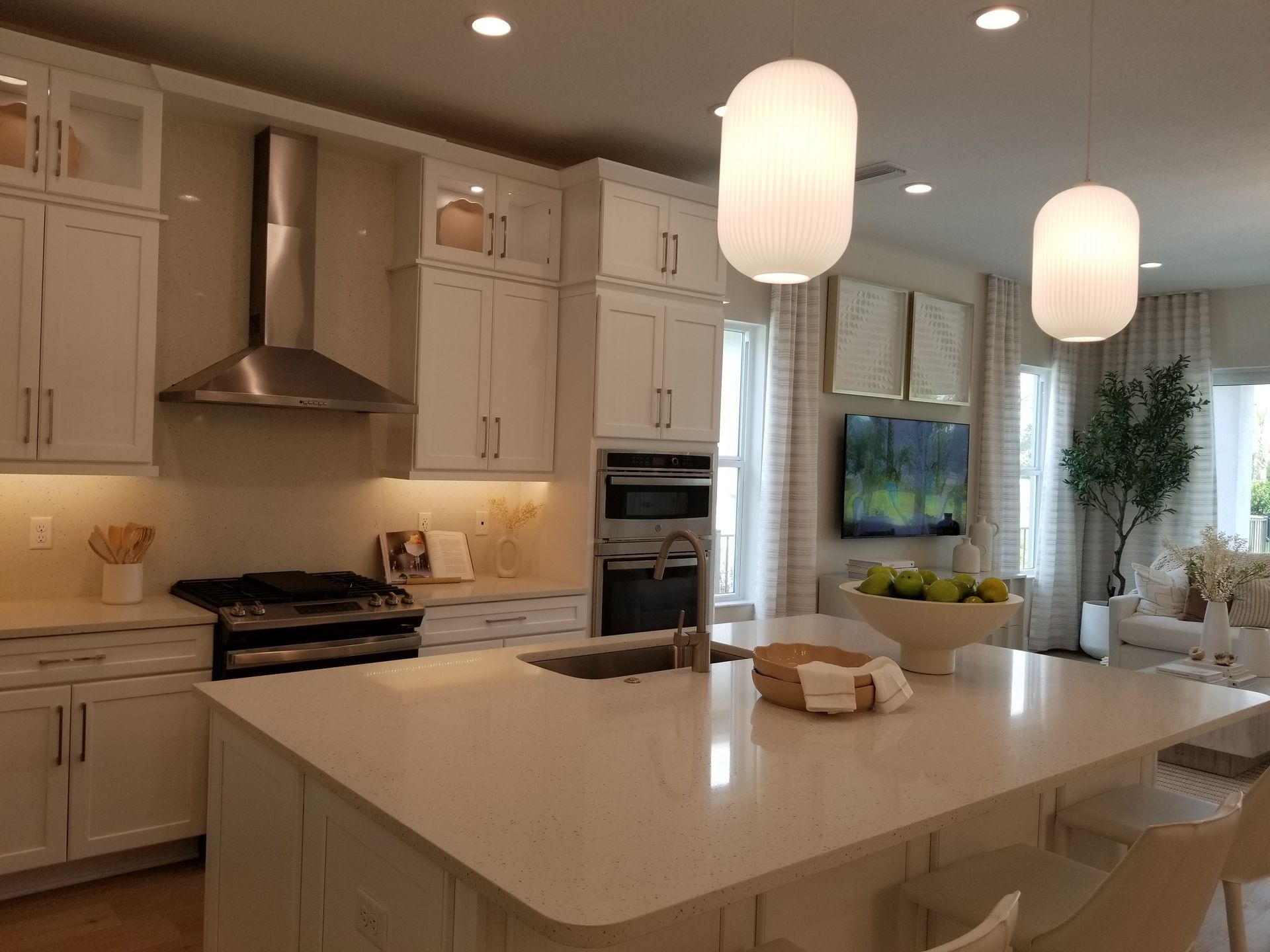 Bright modern kitchen with white cabinets, large island, pendant lights, and a window seat.