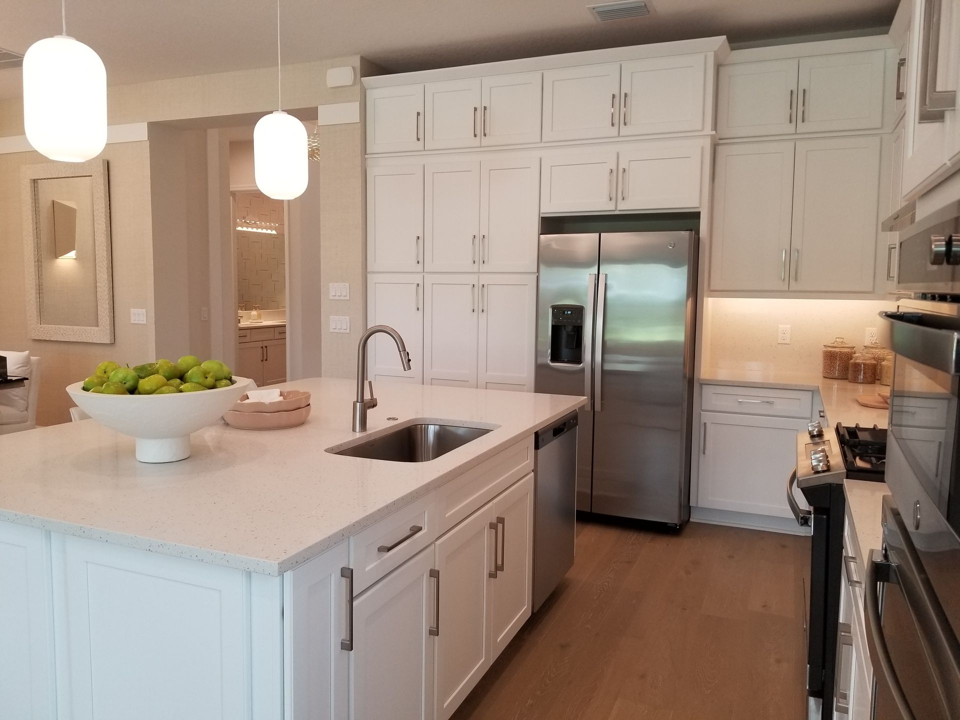 Bright modern kitchen with white cabinets, stainless steel appliances, and a large island with sink.