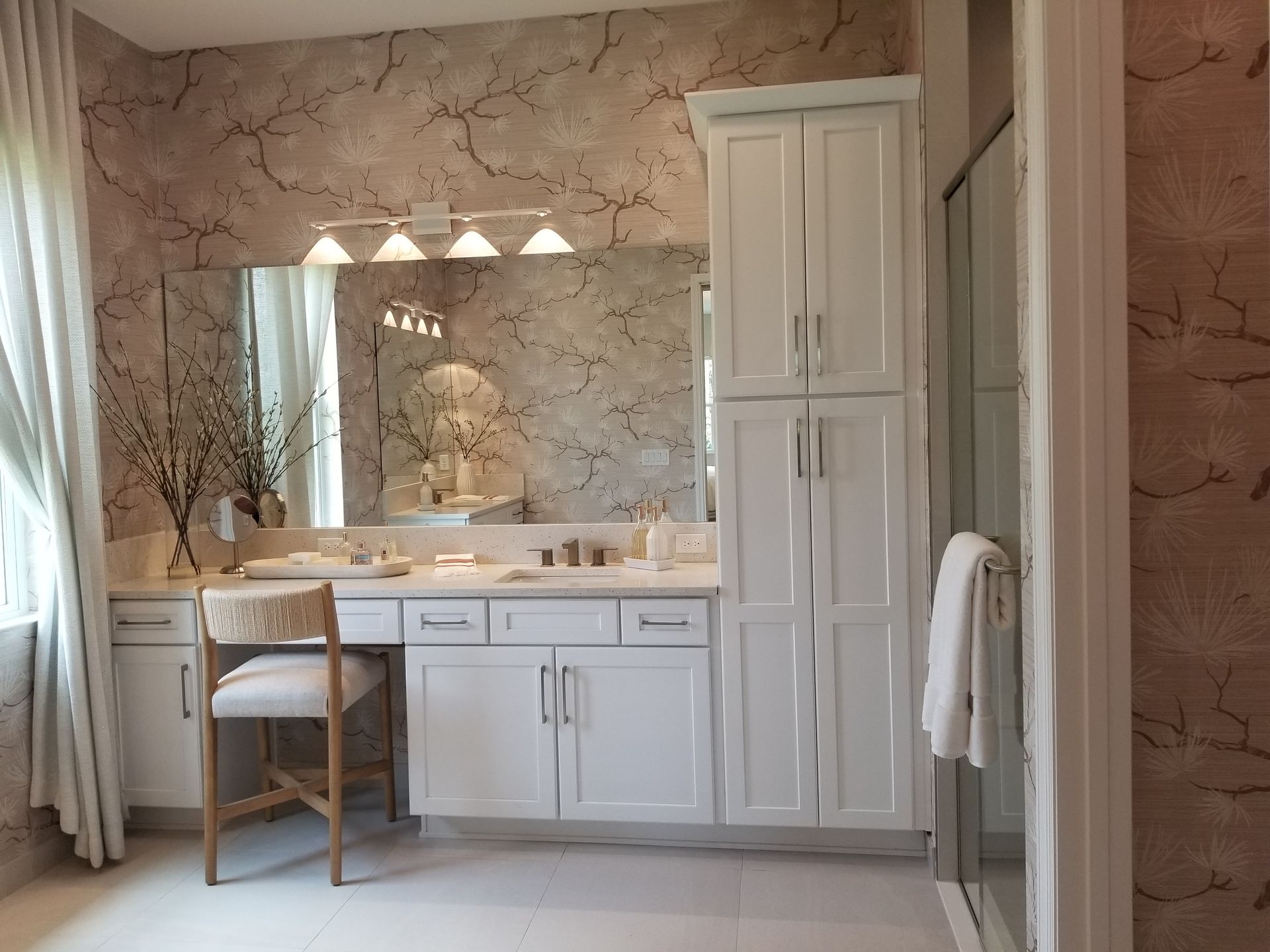 Elegant bathroom vanity with mirror, white cabinetry, and marble-patterned walls and floor lighting