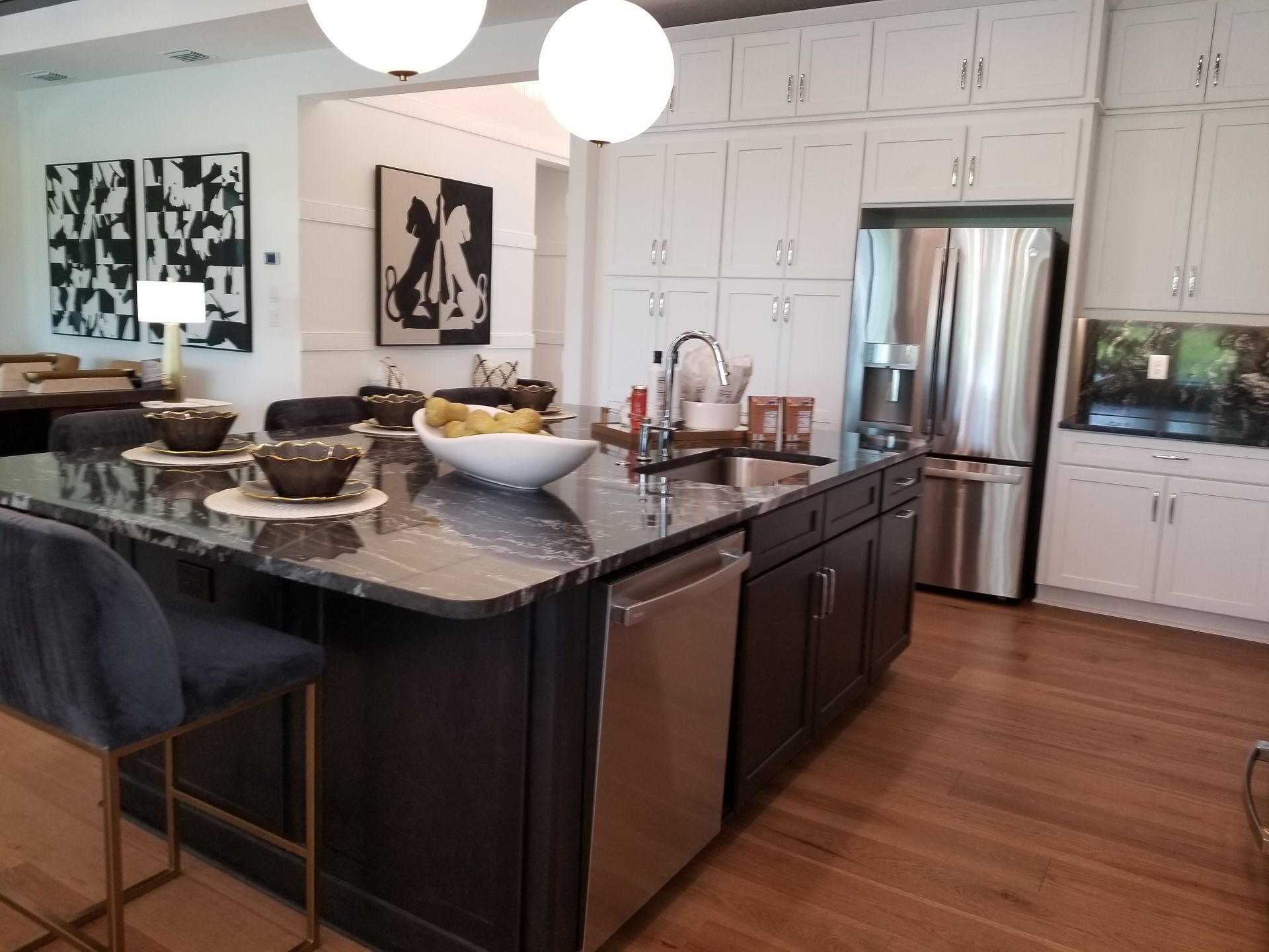 Modern kitchen with dark island, stainless appliances, white cabinets, and pendant lights