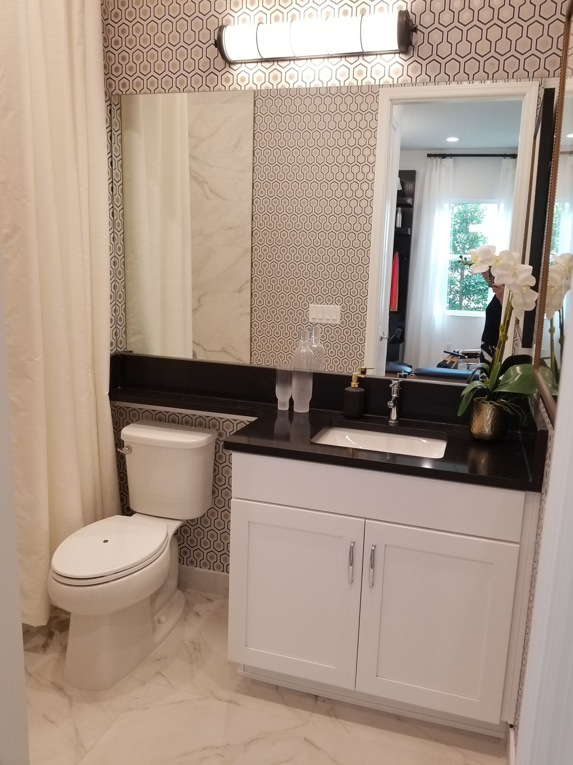 Small bathroom with a toilet, white vanity, black countertop, and large mirror.