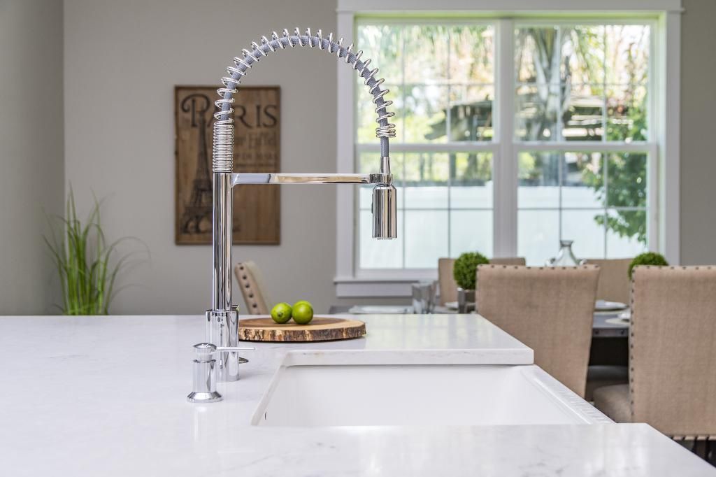 Modern kitchen with white island, chrome faucet, fruit bowl, and bright windows overlooking patio